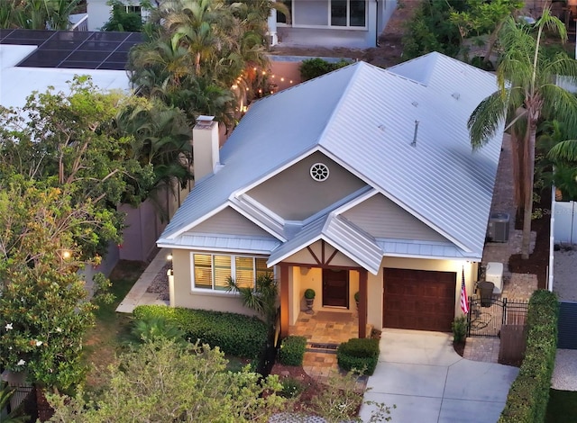 1934 Bougainvillea St, Sarasota, FL 34239 - view of front of home with concrete driveway, a chimney, metal roof, stucco siding, and a garage