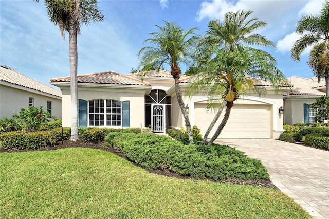 mediterranean / spanish home featuring stucco siding, a garage, driveway, a tile roof, and a front lawn