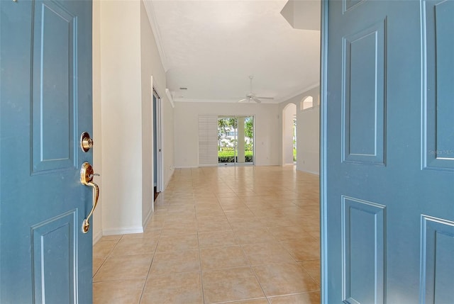 entrance foyer with light tile patterned floors, a ceiling fan, ornamental molding, arched walkways, and baseboards