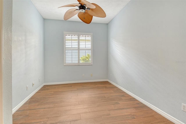 spare room with wood finished floors, a ceiling fan, and baseboards