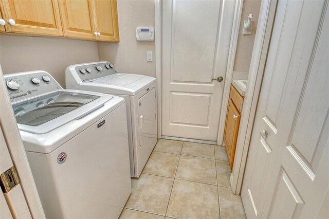 laundry area with separate washer and dryer, cabinet space, and light tile patterned flooring