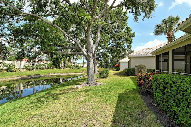 view of grassy yard with a water view and a sunroom