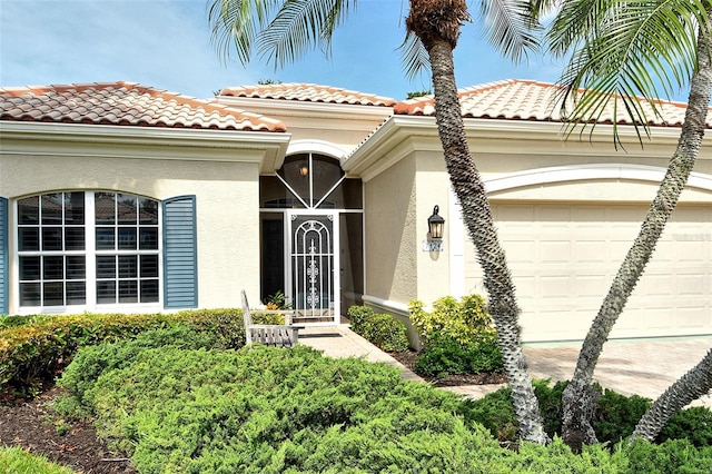 doorway to property featuring a garage, stucco siding, and a tile roof