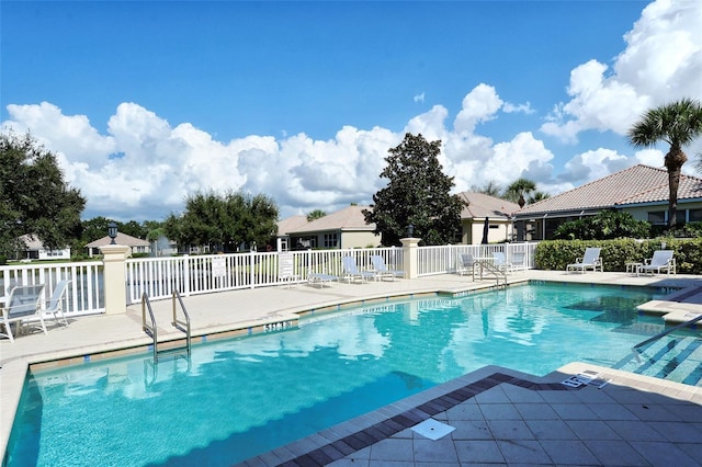 community pool with a patio area and fence