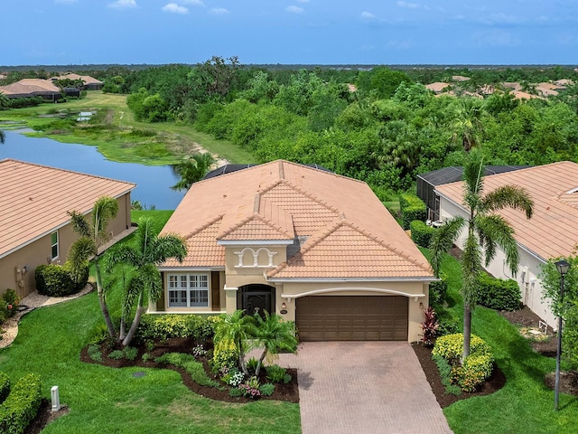 view of front of home with a garage, stucco siding, driveway, a tiled roof, and a water view