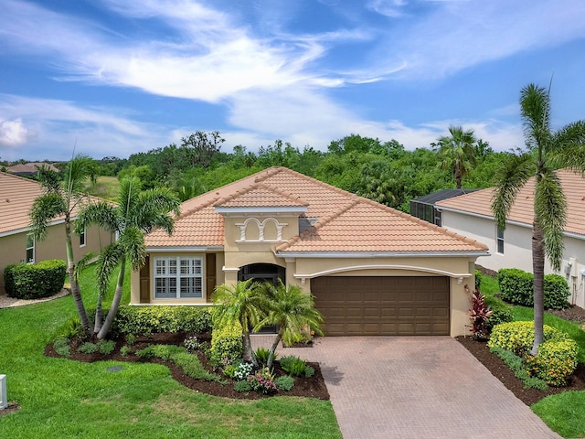mediterranean / spanish-style home with an attached garage, decorative driveway, stucco siding, a front yard, and a tile roof