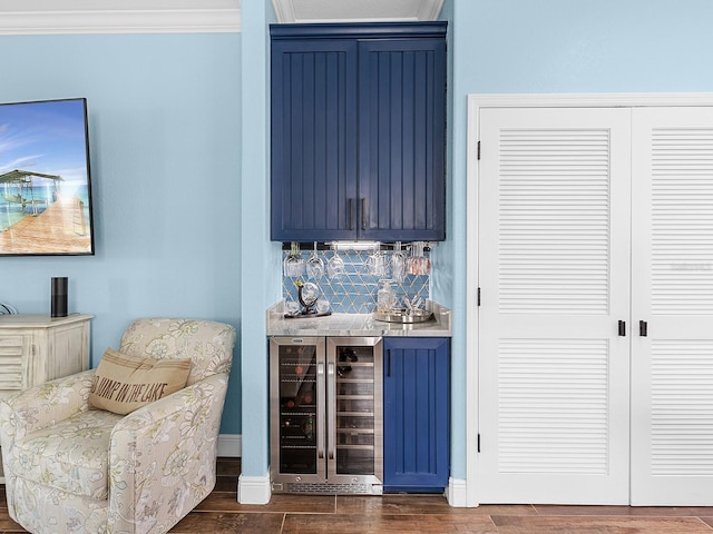 indoor dry bar with beverage cooler, dark wood-type flooring, backsplash, crown molding, and baseboards