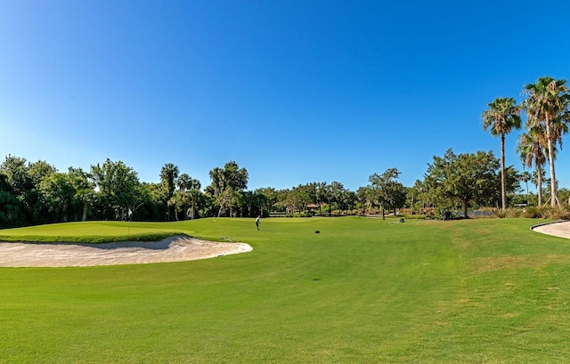 surrounding community with golf course view, view of wooded area, and a yard