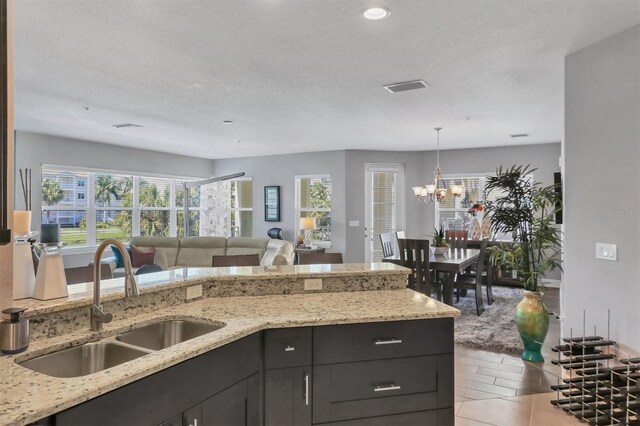 3430 77th St W Unit 103, Bradenton, FL 34209 - kitchen with a sink, light stone counters, pendant lighting, a chandelier, and open floor plan