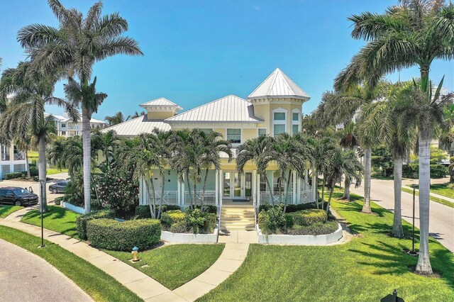 3430 77th St W Unit 103, Bradenton, FL 34209 - view of front of house featuring a standing seam roof, french doors, a front lawn, covered porch, and stucco siding