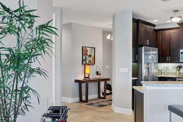 3430 77th St W Unit 103, Bradenton, FL 34209 - kitchen featuring appliances with stainless steel finishes, dark brown cabinetry, light stone counters, baseboards, and light tile patterned floors