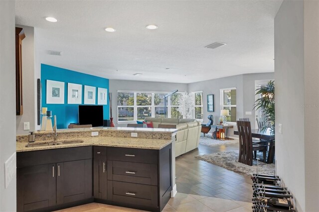 3430 77th St W Unit 103, Bradenton, FL 34209 - kitchen featuring a sink, a peninsula, open floor plan, light stone countertops, and recessed lighting