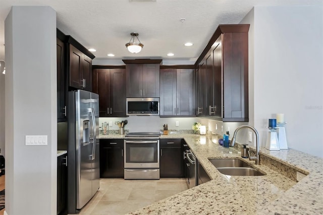 3430 77th St W Unit 103, Bradenton, FL 34209 - kitchen featuring appliances with stainless steel finishes, a sink, light stone counters, recessed lighting, and dark brown cabinets