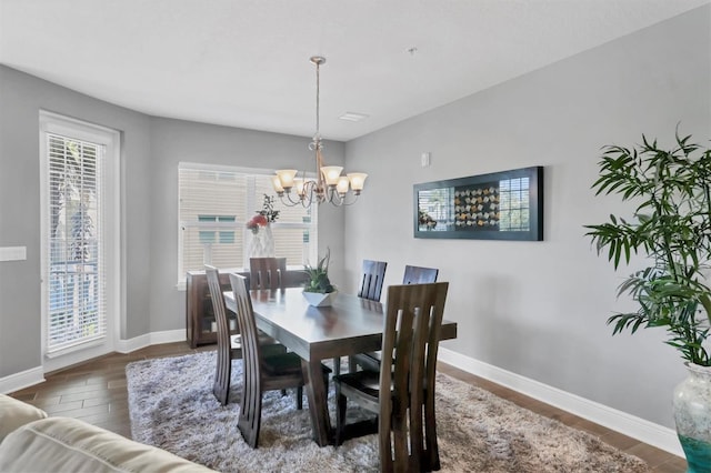 3430 77th St W Unit 103, Bradenton, FL 34209 - dining area featuring a chandelier, baseboards, and wood finished floors