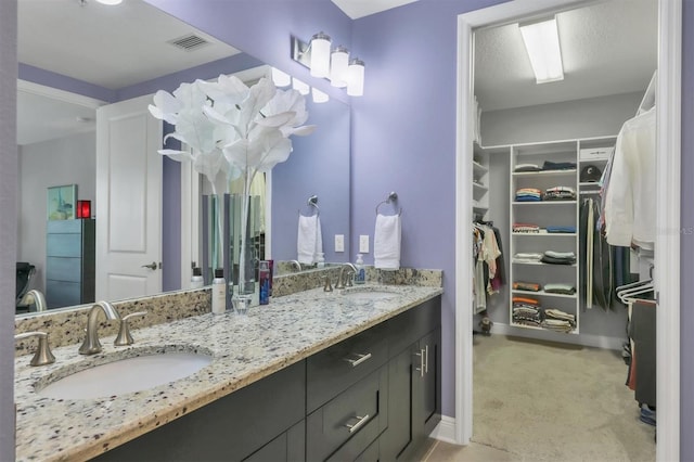 3430 77th St W Unit 103, Bradenton, FL 34209 - full bathroom featuring a spacious closet, double vanity, and baseboards
