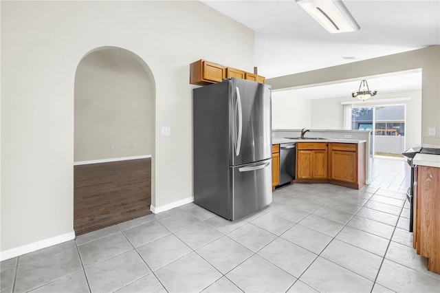 2499 Trimble Ave, North Port, FL 34288 - kitchen with stainless steel appliances, a sink, a peninsula, light countertops, and brown cabinetry