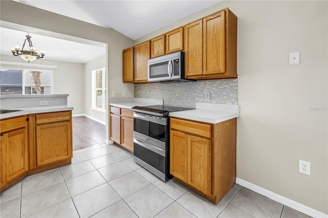 2499 Trimble Ave, North Port, FL 34288 - kitchen with stainless steel appliances, tasteful backsplash, light countertops, a chandelier, and brown cabinets