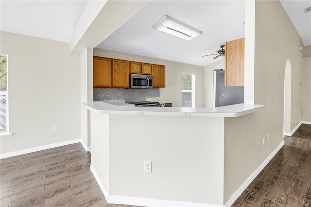 2499 Trimble Ave, North Port, FL 34288 - kitchen with appliances with stainless steel finishes, brown cabinetry, wood finished floors, decorative backsplash, and a ceiling fan