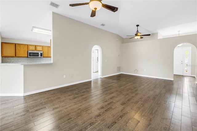 2499 Trimble Ave, North Port, FL 34288 - unfurnished living room featuring arched walkways, ceiling fan, dark wood-style floors, high vaulted ceiling, and baseboards
