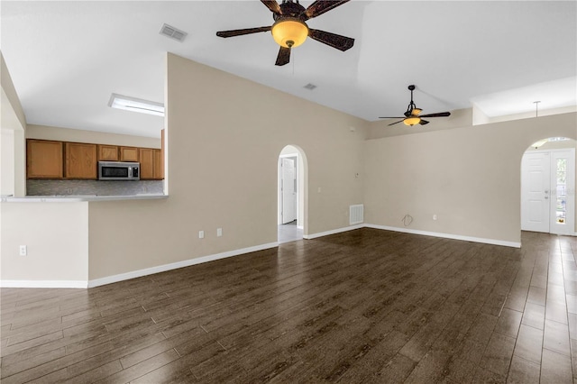 2499 Trimble Ave, North Port, FL 34288 - unfurnished living room featuring arched walkways, ceiling fan, dark wood-style flooring, high vaulted ceiling, and baseboards
