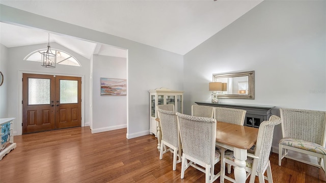 dining area with lofted ceiling, a chandelier, wood finished floors, french doors, and baseboards