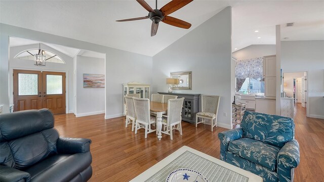living area featuring french doors, ceiling fan, baseboards, wood finished floors, and a chandelier
