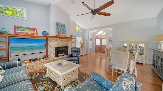 living room featuring high vaulted ceiling, a brick fireplace, a ceiling fan, wood finished floors, and baseboards
