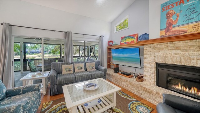 living area with wood finished floors, a fireplace, and vaulted ceiling