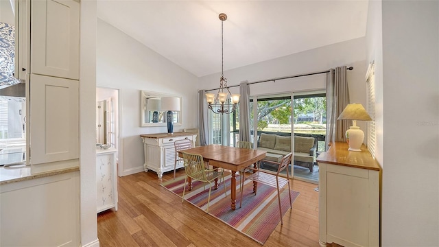 dining space featuring light wood-style flooring, a chandelier, baseboards, and high vaulted ceiling