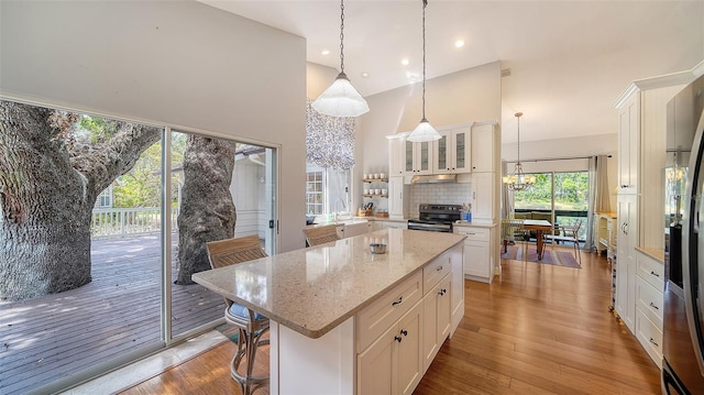 kitchen featuring a chandelier, stainless steel appliances, a sink, a high ceiling, and white cabinets