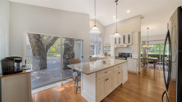 kitchen with a chandelier, appliances with stainless steel finishes, white cabinetry, a sink, and glass insert cabinets