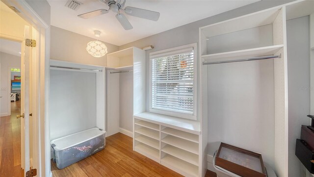 walk in closet with wood finished floors and a ceiling fan