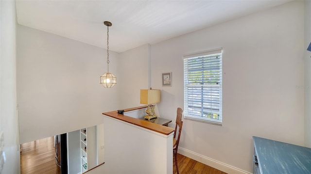 hallway featuring an upstairs landing, wood finished floors, and baseboards