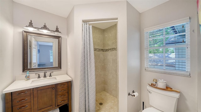 bathroom featuring a tile shower, vanity, and toilet