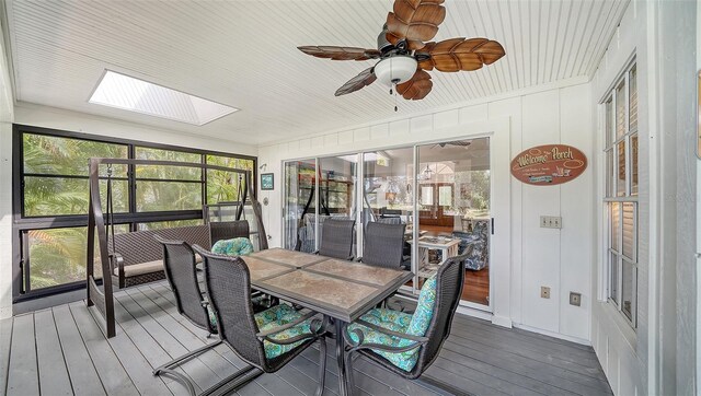 sunroom with ceiling fan, a skylight, and outdoor dining space