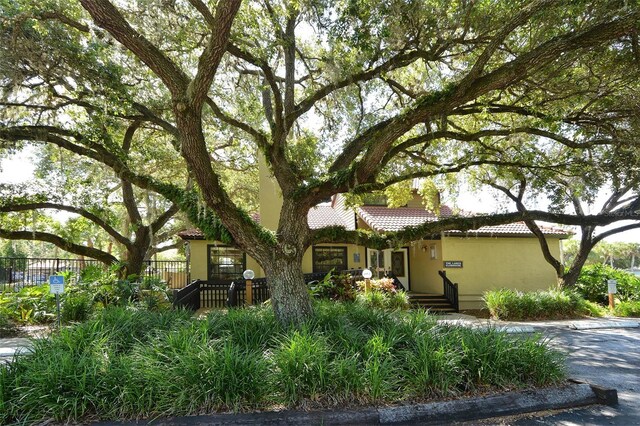 view of front of house with stucco siding, fence, a tiled roof, and a chimney