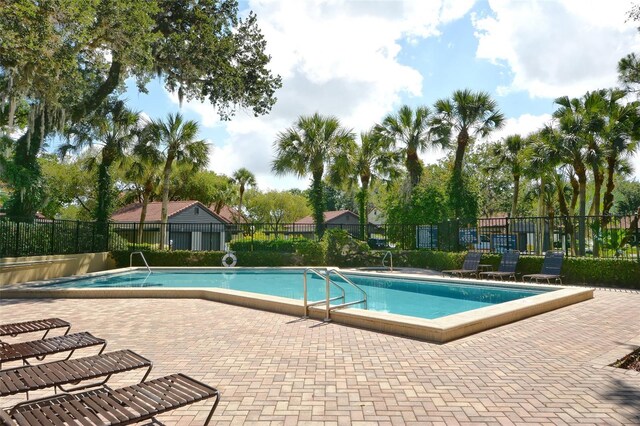 community pool with a patio and fence
