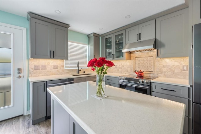 kitchen featuring under cabinet range hood, a sink, gray cabinets, and recessed lighting