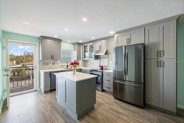 kitchen with appliances with stainless steel finishes, gray cabinets, under cabinet range hood, backsplash, and recessed lighting