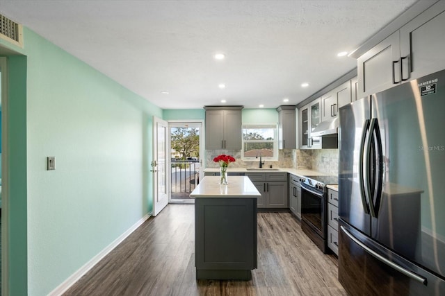kitchen featuring stainless steel appliances, a sink, gray cabinetry, wood finished floors, and recessed lighting