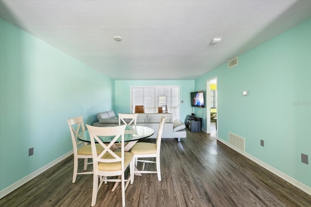 dining space featuring dark wood-type flooring and baseboards