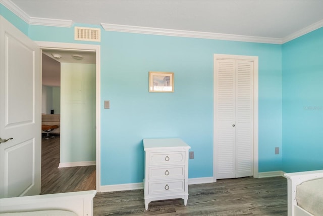 bedroom featuring dark wood-type flooring, ornamental molding, baseboards, and a closet