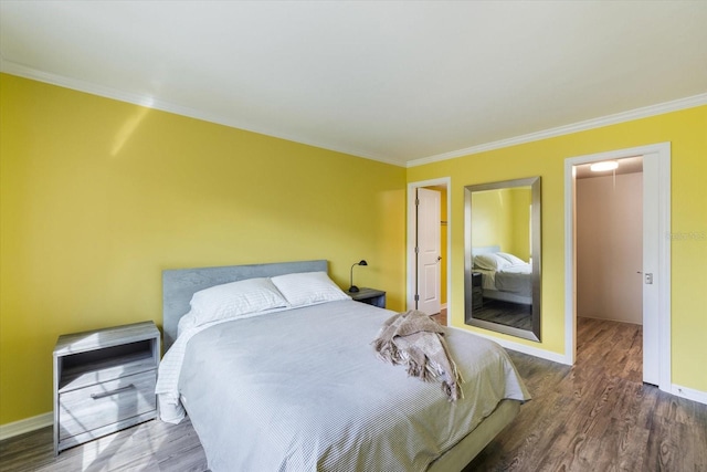 bedroom featuring wood finished floors, crown molding, and baseboards