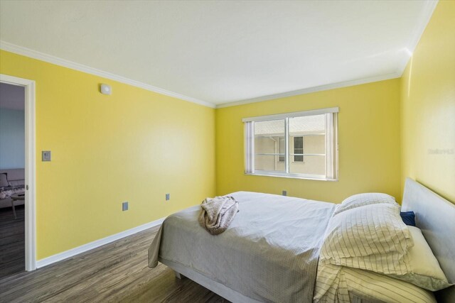 bedroom with wood finished floors, baseboards, and ornamental molding