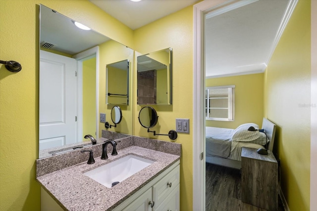 bathroom featuring wood finished floors, vanity, ensuite bath, and ornamental molding