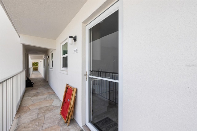 view of exterior entry featuring stucco siding and a balcony