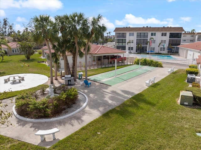 view of community featuring shuffleboard, a lawn, and a residential view