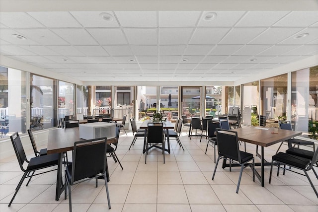 dining area featuring a drop ceiling and light tile patterned flooring