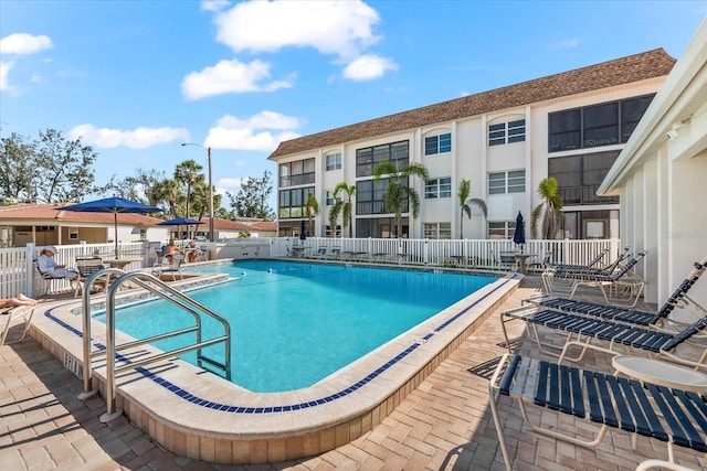 community pool with fence and a patio area