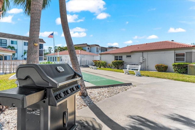 view of patio with area for grilling, shuffleboard, fence, and a residential view